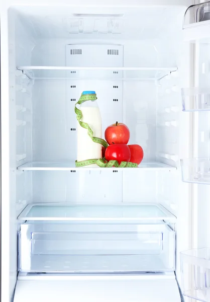 Conceptual photo of diet: apple and milk bottle with measuring type on shelf of refrigerator — Stock Photo, Image