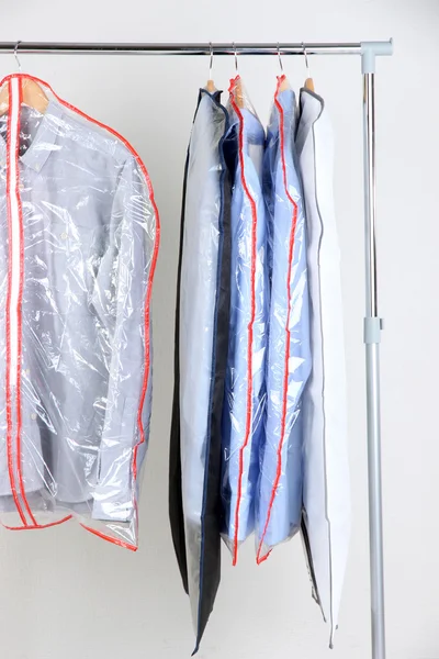 Office male clothes in cases for storing on hangers, on gray background — Stock Photo, Image