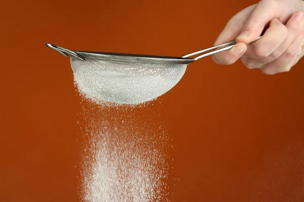 Sieve and powdered sugar on orange background — Stock Photo, Image