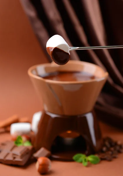 Fondue de chocolate con caramelos de malvavisco, sobre fondo marrón — Foto de Stock