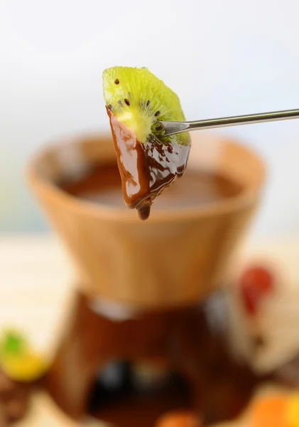 Fonduta al cioccolato con frutta, su tavolo di legno, su fondo chiaro — Foto Stock