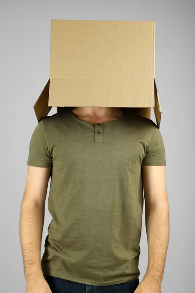 Hombre con caja de cartón en la cabeza sobre fondo gris —  Fotos de Stock