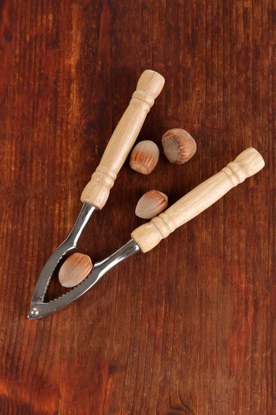 Nötknäppare med nötter på träbord närbild — Stockfoto