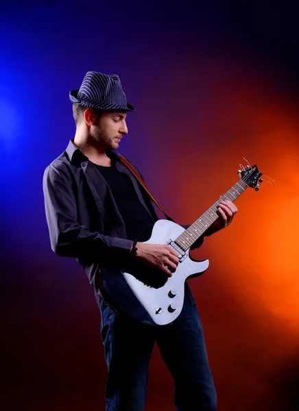 진한 색 바탕에 기타를 연주하는 젊은 음악가 — 스톡 사진