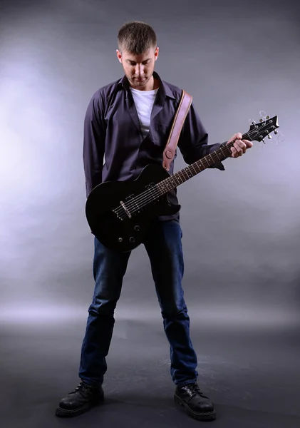 Young musician playing guitar on gray background — Stock Photo, Image