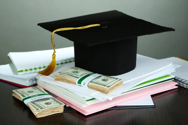 Dinero para graduación o entrenamiento en mesa de madera sobre fondo gris —  Fotos de Stock