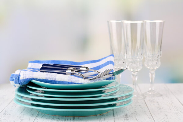 Clean dishes on wooden table on light background