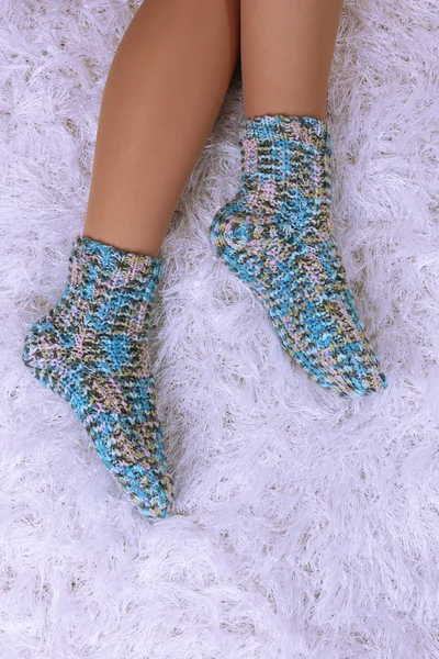 Patas femeninas en calcetines de colores sobre fondo de alfombra blanca —  Fotos de Stock