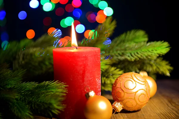 Композиция с горящей свечой, елкой и рождественскими украшениями на фоне разноцветных огней — стоковое фото