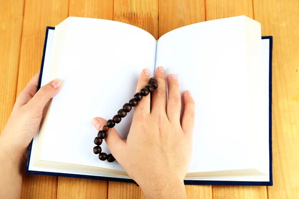 Handen met rozenkrans en heilige boek, op lichte achtergrond — Stockfoto