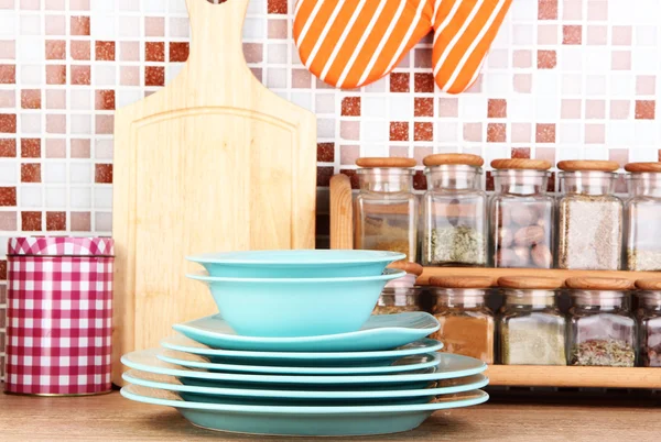 Plates in kitchen on table on mosaic tiles background — Stock Photo, Image