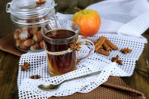 Bevanda calda in tazza di vetro con frutta e spezie, su fondo di legno — Foto Stock