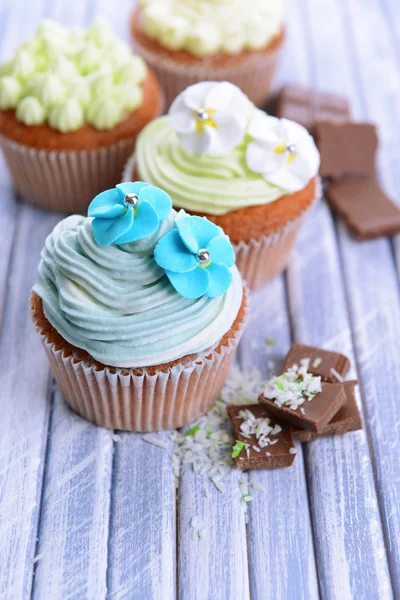 木製の背景の色に、バター クリームとおいしいカップケーキ — ストック写真