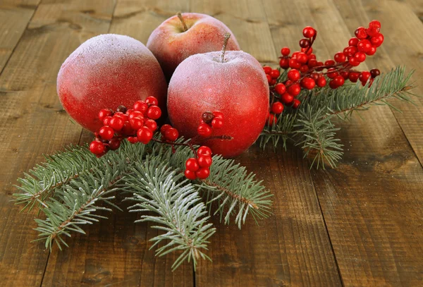 Pommes rouges avec branche de sapin et baies sur fond en bois — Photo