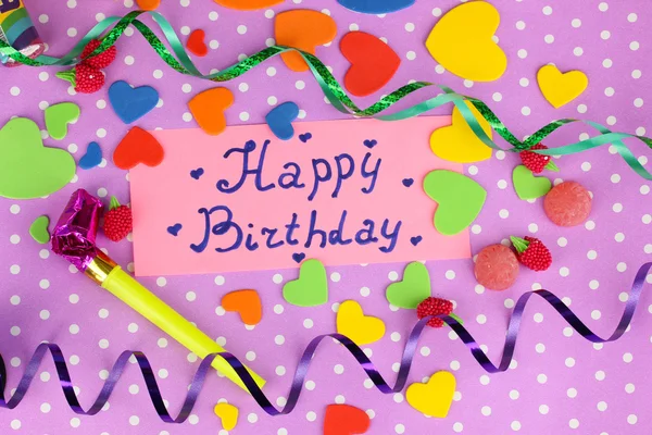 Cartão "Feliz Aniversário" cercado por elementos festivos em fundo roxo — Fotografia de Stock