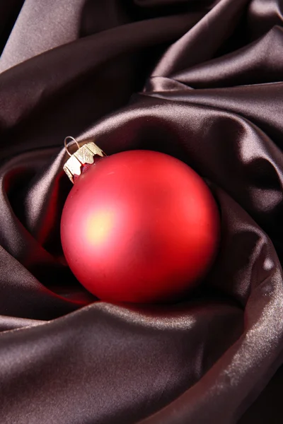 Beautiful Christmas ball on brown satin cloth — Stock Photo, Image