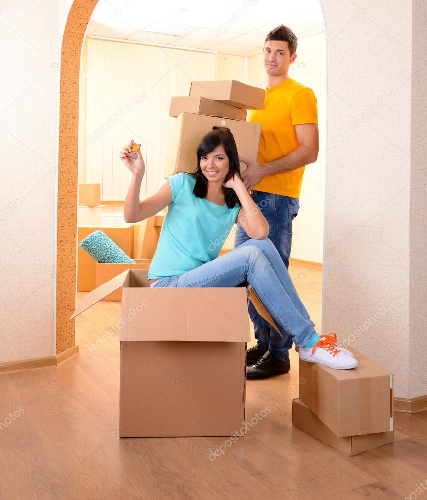Young couple fooling around in new house on room background