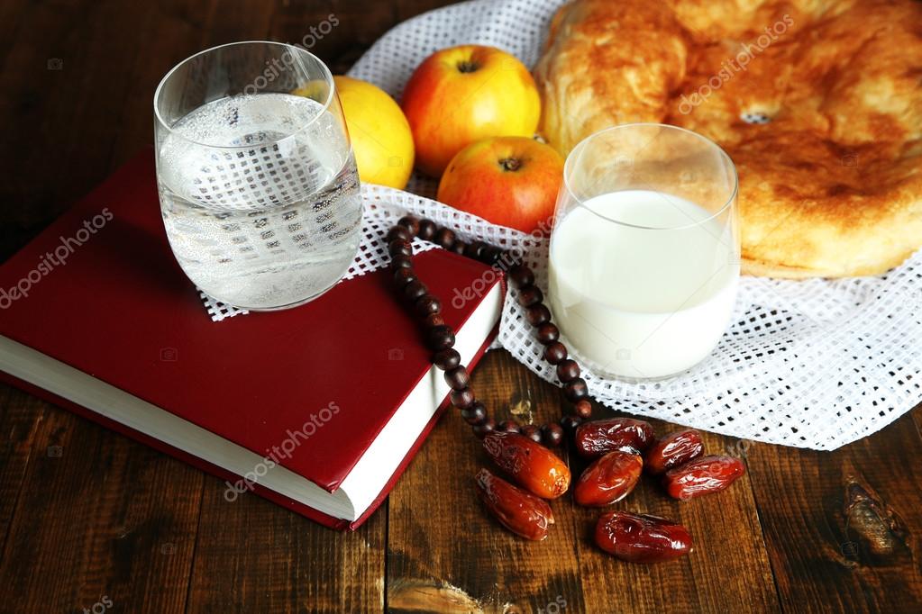 Composition with traditional Ramadan food, holy book and rosary, on wooden background