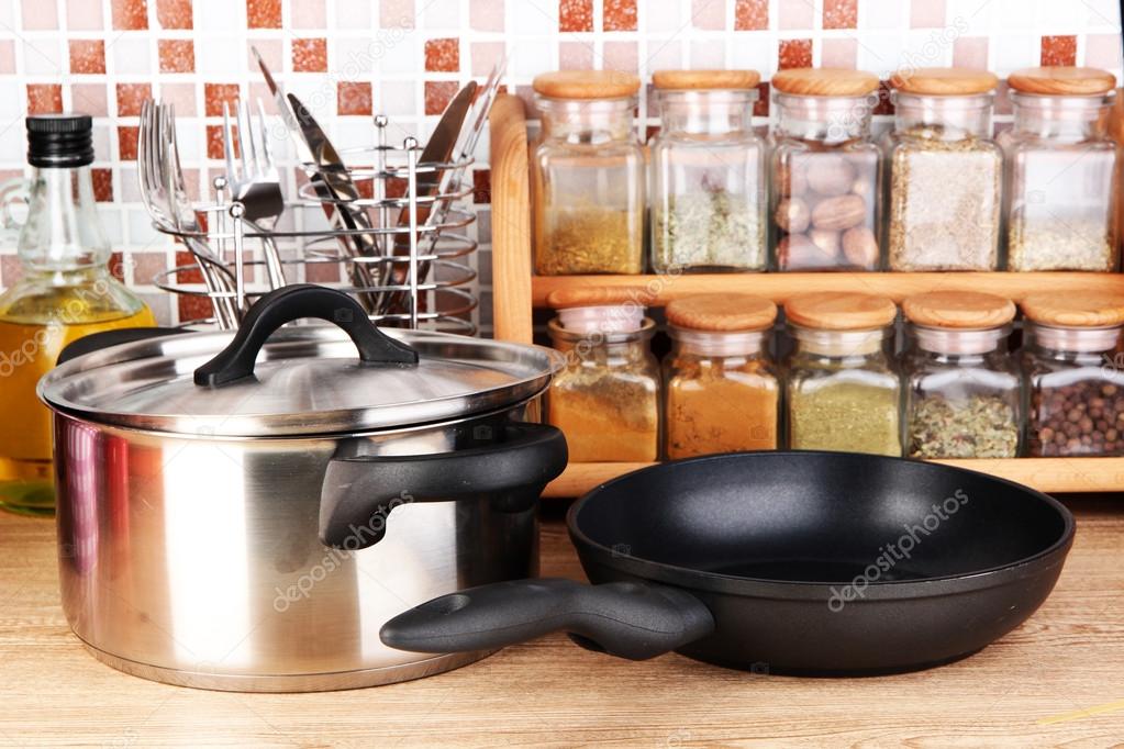 Pot and pan in kitchen on table on mosaic tiles background