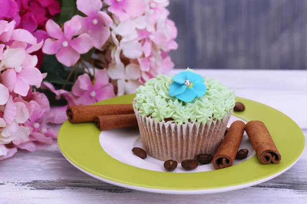 Finom cupcake vaj tejszín, lemez, színes fából készült háttér — Stock Fotó