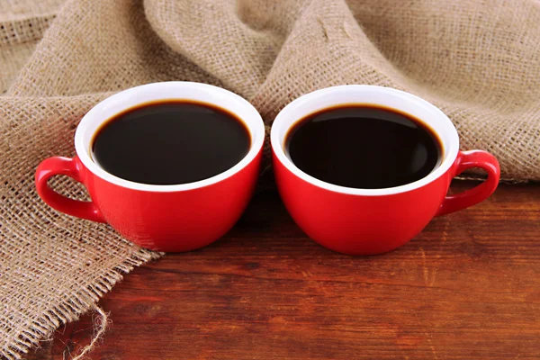 Rote Tassen starken Kaffee auf dem Tisch auf Sacktuch Hintergrund — Stockfoto