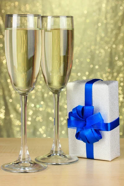 Glasses of champagne with gift box on shiny background — Stock Photo, Image