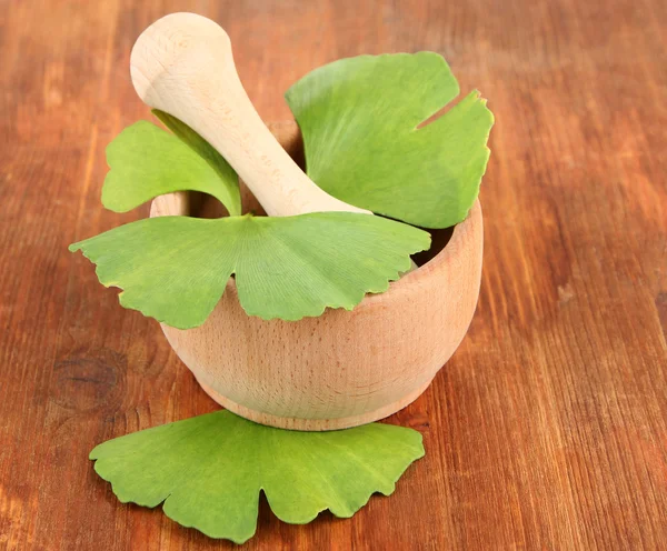 Ginkgo biloba leaves in mortar and pills on wooden background — Stock Photo, Image