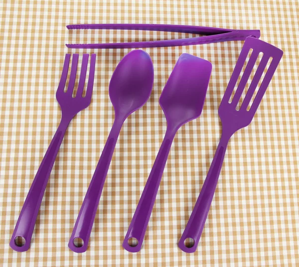 Plastic kitchen utensils on fabric background — Stock Photo, Image