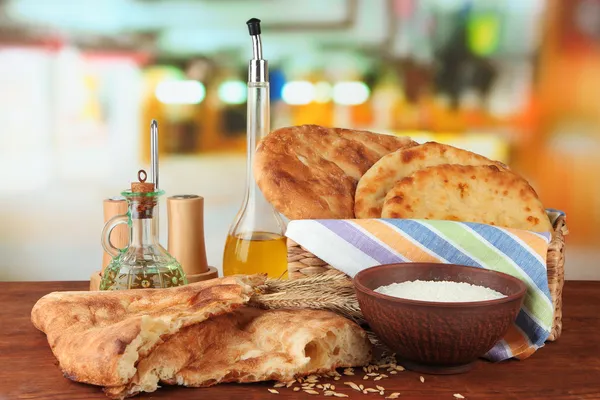 Pane pita in cesto con spezie e farina sul tavolo su sfondo brillante — Foto Stock