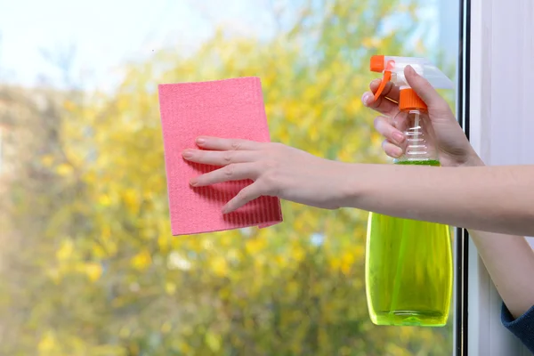 Manos con spray limpiando la ventana — Foto de Stock