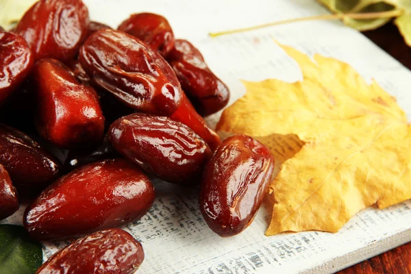 Dried dates with yellow leaves on wooden background — Stock Photo, Image