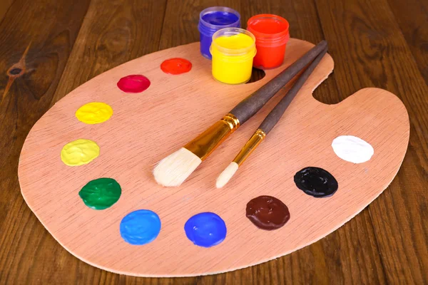 Palette d'art en bois avec peinture et pinceaux sur table close-up — Photo