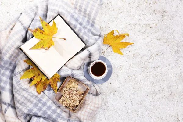 Komposition mit warmem Karo, Buch, Tasse Heißgetränk auf farbigem Teppich Hintergrund — Stockfoto