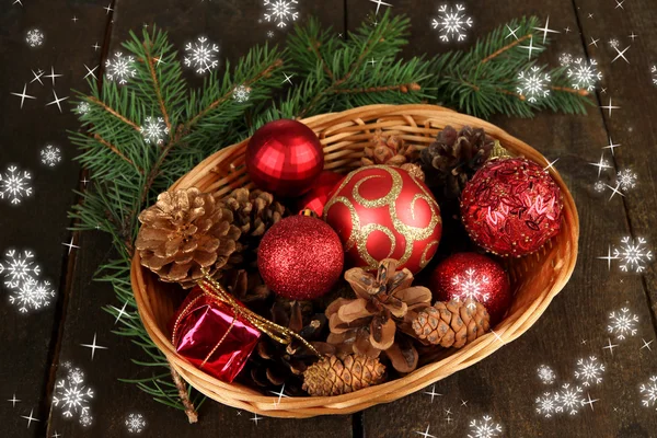 Christmas decorations in basket and spruce branches on wooden background — Stock Photo, Image