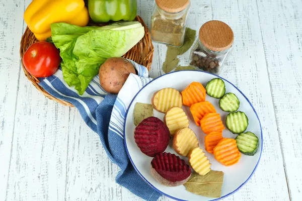 Красивые нарезанные овощи, на тарелке, на деревянном фоне — стоковое фото