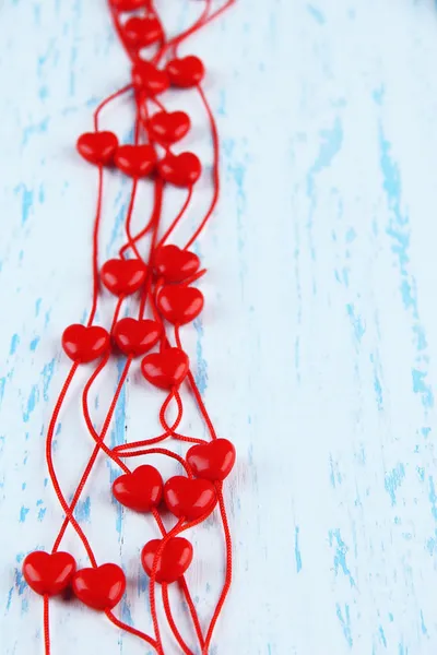 Heart-shaped beads on string on wooden background — Stock Photo, Image