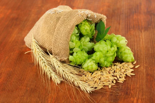 Verse groene hop in jute zak en gerst, op houten achtergrond — Stockfoto