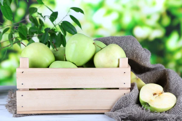 Juicy apples in box on wooden table on nature background — Stock Photo, Image