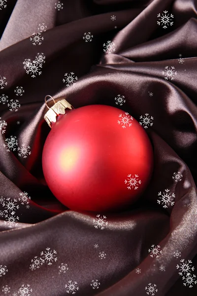 Schöne Weihnachtskugel auf braunem Satintuch — Stockfoto