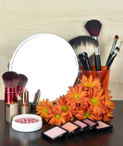 Espejo de mesa redonda con cosméticos y flores sobre mesa sobre fondo de madera — Foto de Stock