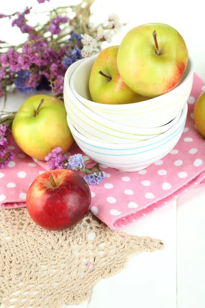 Saftige Äpfel auf Teller auf weißem Holztisch — Stockfoto