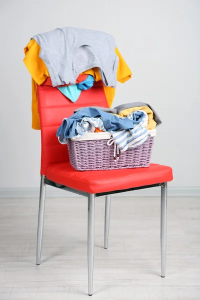 Un mucchio di vestiti sulla sedia a colori, su sfondo grigio — Foto Stock