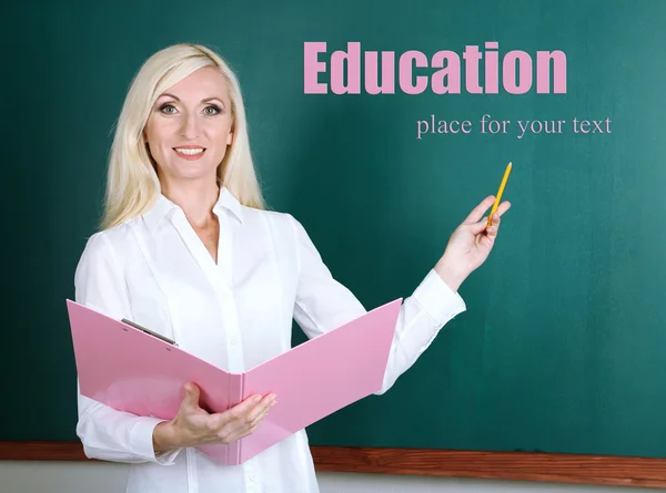 School teacher with folder near blackboard in classroom — Stock Photo, Image