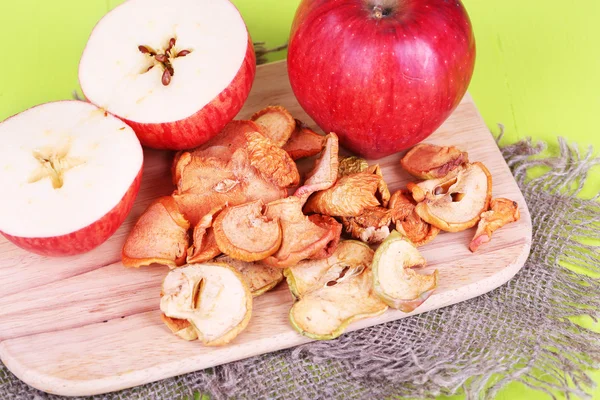 Pommes séchées, sur planche à découper, sur fond de bois couleur — Photo