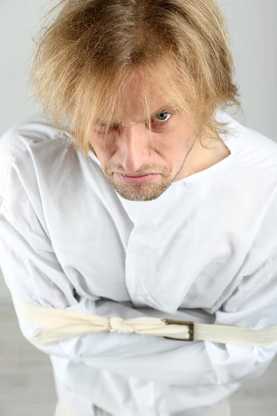 Hombre mentalmente enfermo con camisa de fuerza sobre fondo gris — Foto de Stock