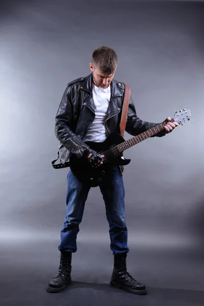 Joven músico tocando la guitarra sobre fondo gris —  Fotos de Stock