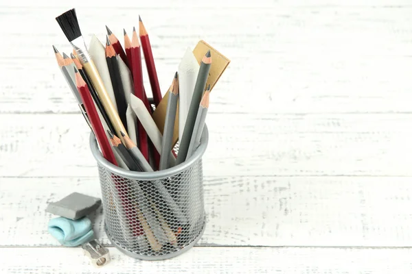 Professional art materials in metal holder, on wooden table — Stock Photo, Image
