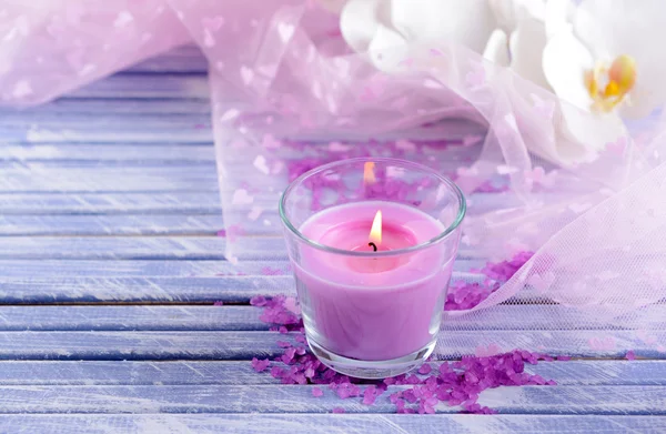 Belas velas coloridas e flores de orquídea, na cor de fundo de madeira — Fotografia de Stock