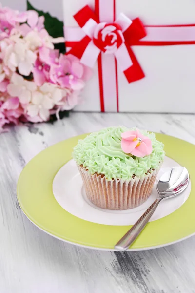Вкусный кекс со сливочным кремом, на тарелке, на цветном деревянном фоне — стоковое фото