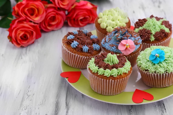 Cupcakes saborosos com creme de manteiga, na placa, na cor de fundo de madeira — Fotografia de Stock